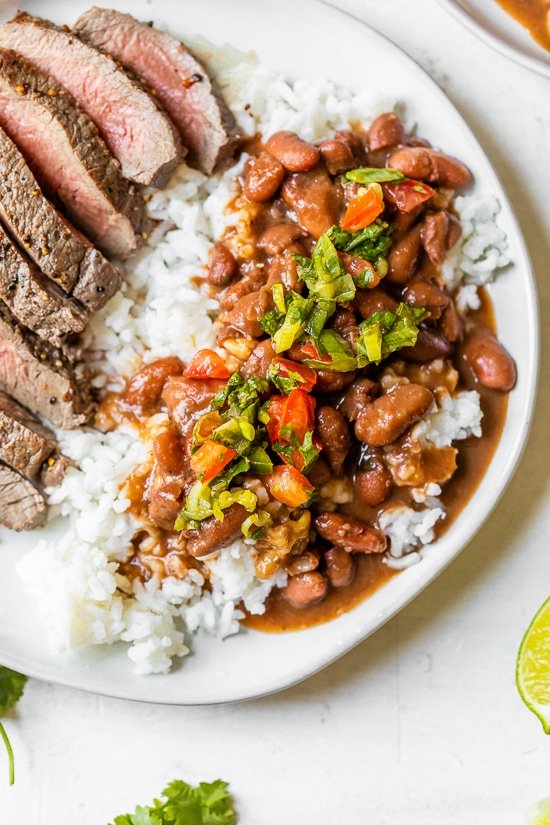 Dominican Beans over rice with aji picante on top and steak on the side.