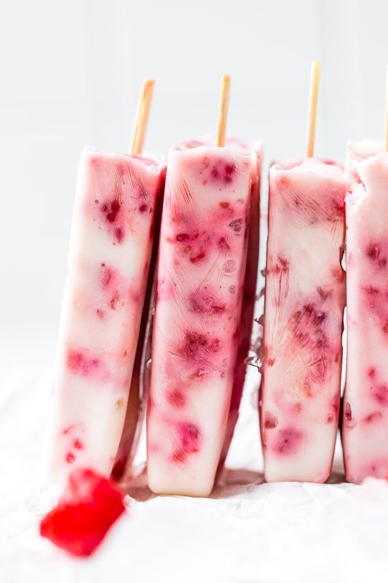 Raspberry Yogurt Ice Pops stacked on a white background.