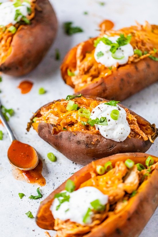 Slow Cooker Chicken Enchilada Stuffed Sweet Potatoes with sour cream and a spoon.