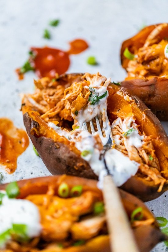 Slow Cooker Chicken Enchilada Stuffed Sweet Potatoes with a fork and sour cream.